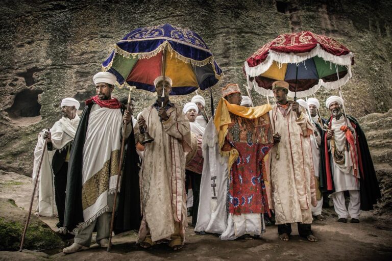 Los sacerdotes ortodoxos, vestidos con llamativos colores y bajo brillantes paraguas, procesionan los tabots, réplicas del Arca de la Alianza.